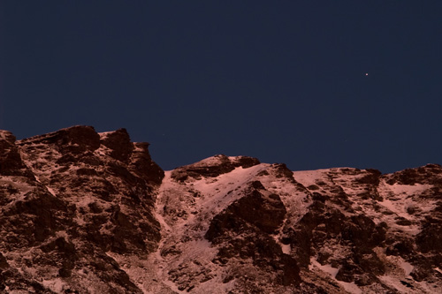 Picture of evening star over winter mountain bathed in red sunset reflection