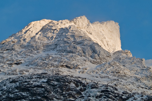 Picture of first sunlight shining on snow cowered mountain peak in Northern Norway