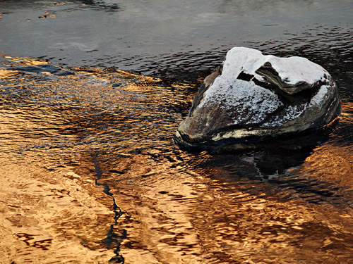 Picture of golden reflections in water and a snowy stone