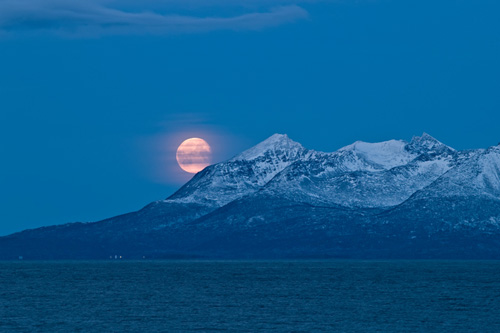 Picture of moon over a snow covered Senja